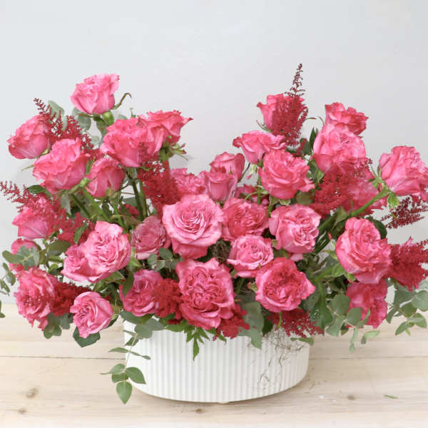 Pink rose arrangement in a white ribbed vase