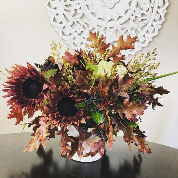 Autumn bouquet with dark sunflowers in a white vase