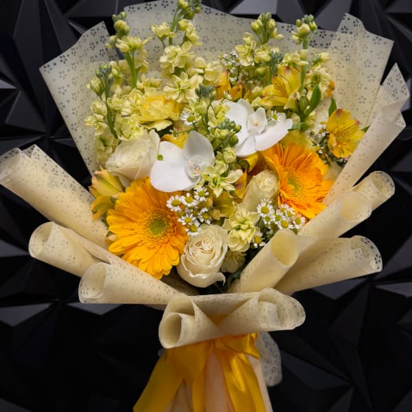 Bouquet of yellow and white flowers wrapped in cream paper
