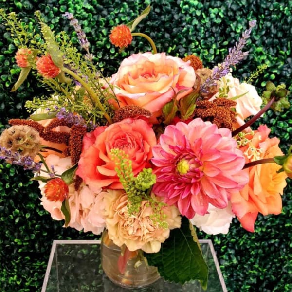 Peach and pink roses with a large pink dahlia in a glass vase