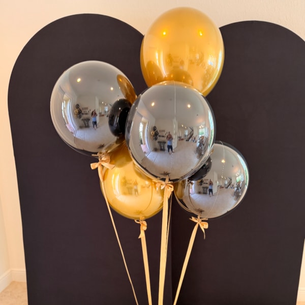 Cluster of metallic gold and silver balloons against a dark backdrop