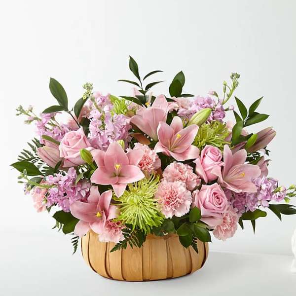 Pink lilies, roses, and carnations in a pumpkin-shaped basket
