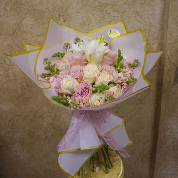 Bouquet of pink and white roses wrapped in pale paper with a pink ribbon