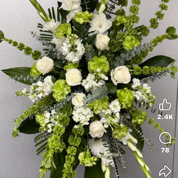 White roses and green flowers in a tall standing arrangement