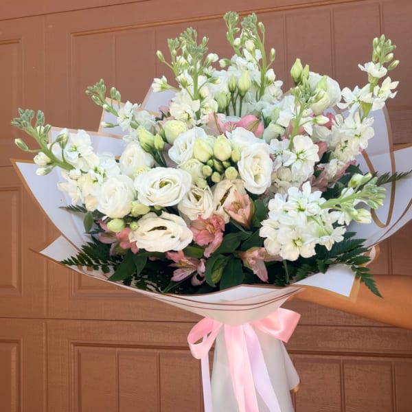 White and pink mixed bouquet wrapped in paper with a pink ribbon