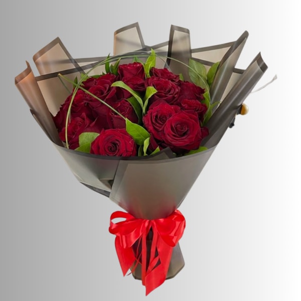 Bouquet of red roses wrapped in dark paper with a red ribbon