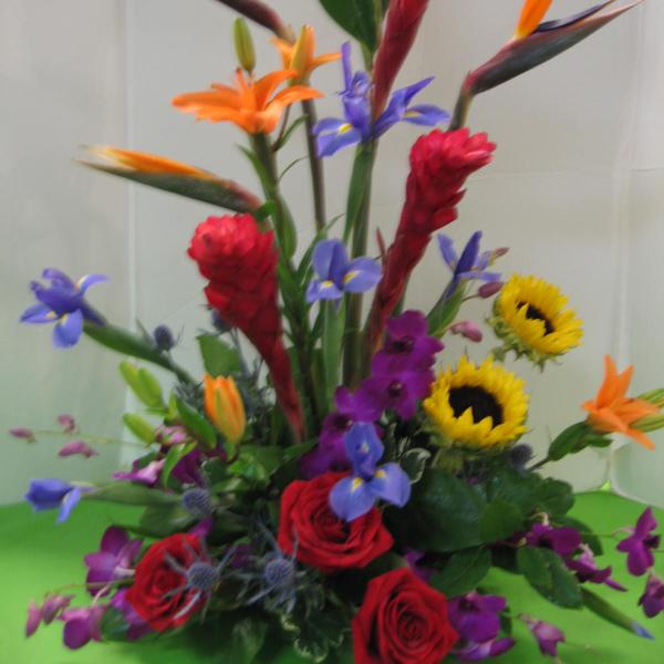 Tall tropical bouquet with red roses, sunflowers, and purple flowers