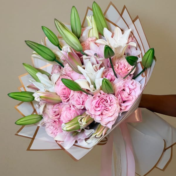 Bouquet of pink roses and white lilies wrapped in white paper