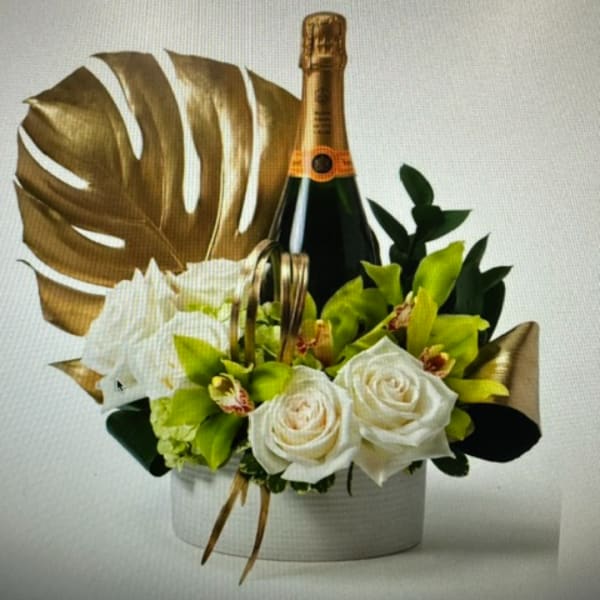 White roses and green orchids arranged with a champagne bottle in a white box