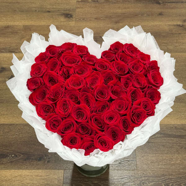 Heart-shaped bouquet of red roses wrapped in white paper