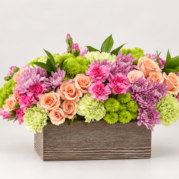 Mixed bouquet of pink, peach, and green flowers in a wooden box