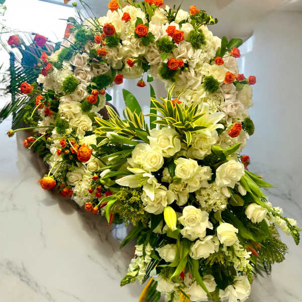 Large white floral wreath with orange rose accents and green foliage