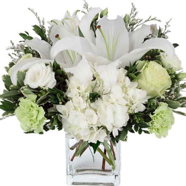 White lilies and roses arranged in a clear glass vase