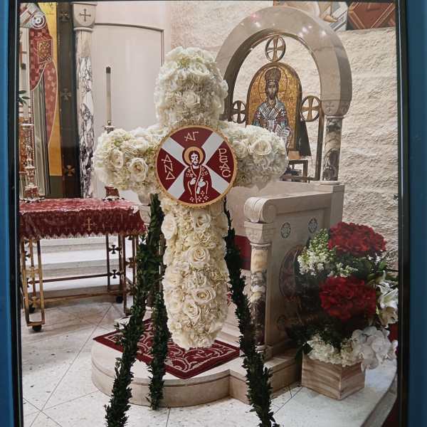 White floral cross standing in a church interior with red accents