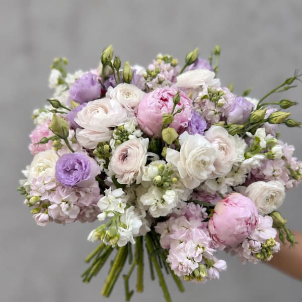 Handheld bouquet of pale pink, white, and lavender flowers