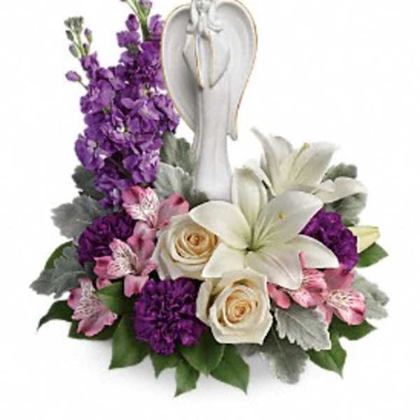 Purple and white floral arrangement with an angel figurine