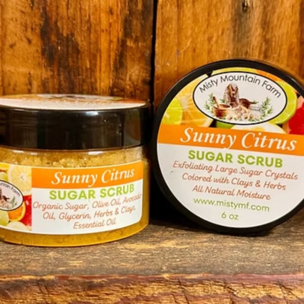 Two jars of Sunny Citrus sugar scrub on a wooden surface.