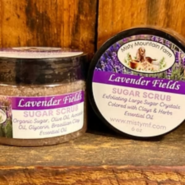 Two lavender sugar scrub jars on a wooden surface.
