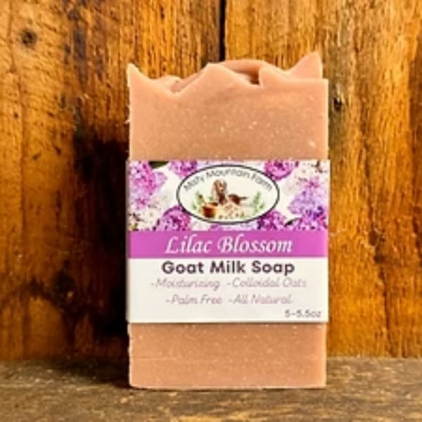 Bar of lilac blossom goat milk soap with a paper label