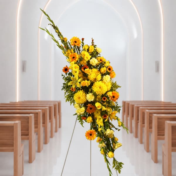 Tall yellow and orange floral spray on a stand in a church aisle
