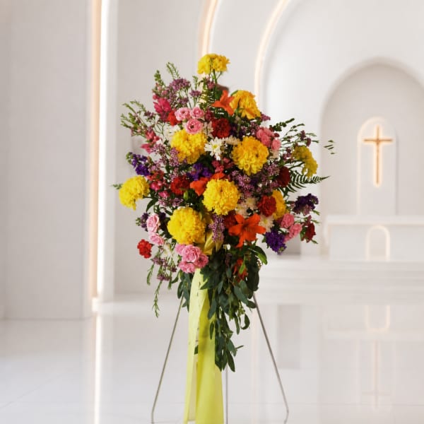 Tall mixed flower arrangement with yellow, pink, red, and purple blooms on a stand