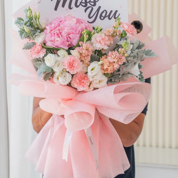 Pink and white bouquet wrapped in pastel pink paper with a thank-you card