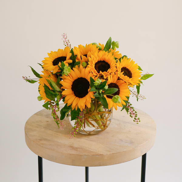 Sunflower arrangement in a clear glass vase on a round table