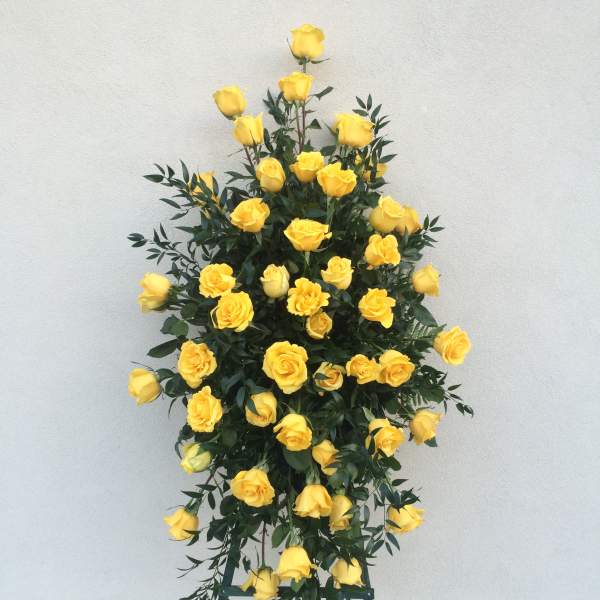 Tall standing arrangement of yellow roses on a metal easel