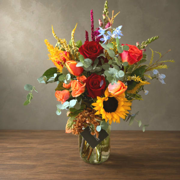 Mixed bouquet of roses and a sunflower in a glass vase