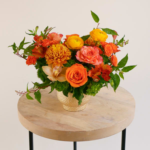 Orange and yellow mixed bouquet in a textured gold vase