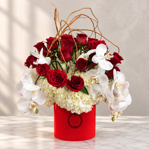 Red roses and white orchids arranged in a red box with curly branches