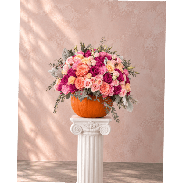 Pink and peach rose arrangement in a pumpkin vase on a pedestal