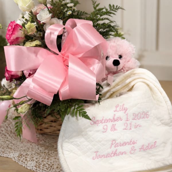 Pink and white flower basket with a teddy bear and embroidered baby blanket