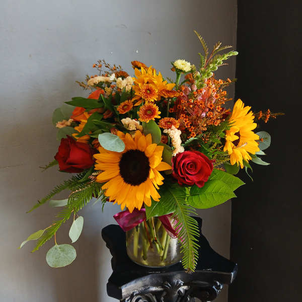Bouquet of sunflowers and red roses in a glass vase