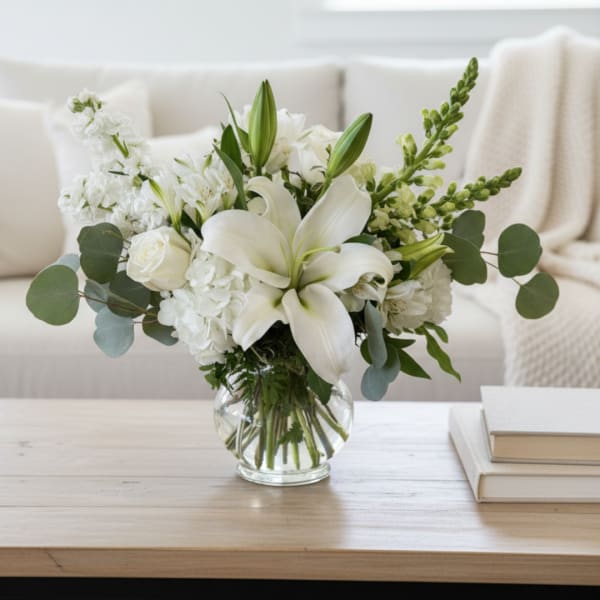 White lilies and roses arranged in a clear glass vase