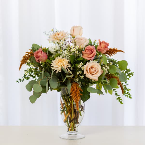 Mixed bouquet of peach and pink roses in a clear glass vase