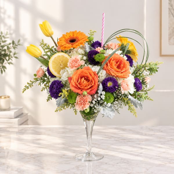 Colorful flower arrangement in a clear glass vase with a striped candle and lemon slice