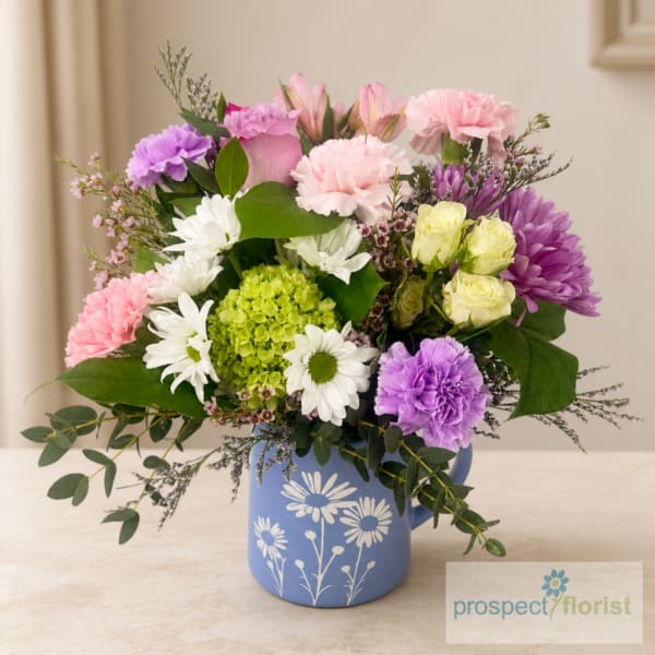 Mixed pink, purple, white, and yellow flowers in a blue vase