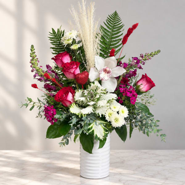 Pink and white mixed bouquet in a white vase with tall grasses