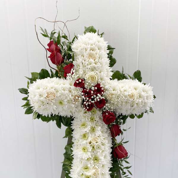 White floral cross with red roses on an easel