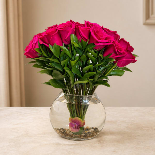 Pink roses arranged in a clear glass bowl vase with pebbles