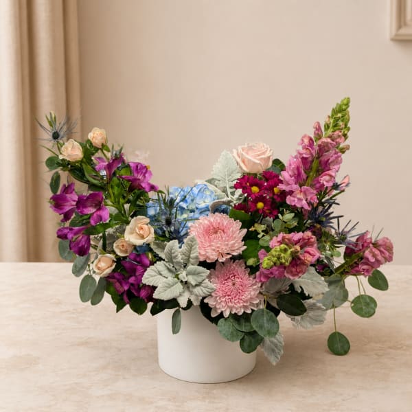 Mixed bouquet in a white vase with pink, purple, and blue flowers