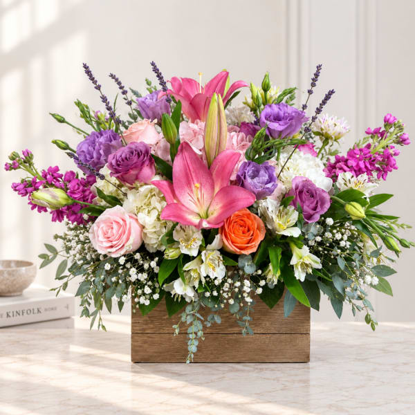 Mixed bouquet with pink lilies, purple roses, and a wooden box