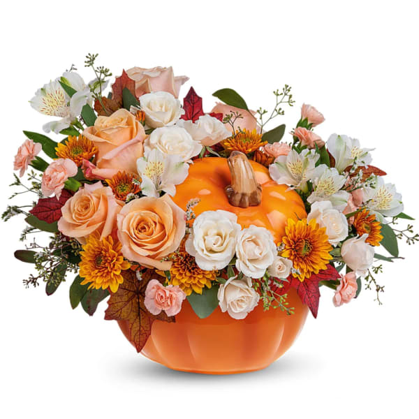 Pumpkin-shaped vase with peach and white flowers and autumn leaves