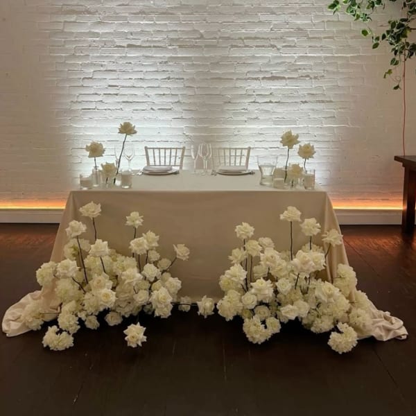 White floral wedding table display with roses and hydrangeas around a draped table