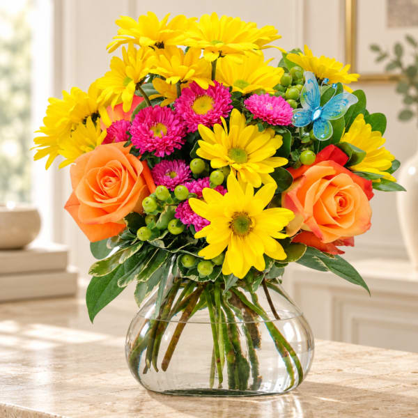 Bouquet of yellow daisies, pink mums, and orange roses in a glass vase