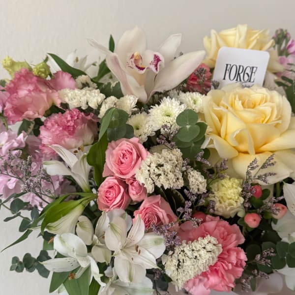 Mixed bouquet with pink and yellow roses, white lilies, and carnations