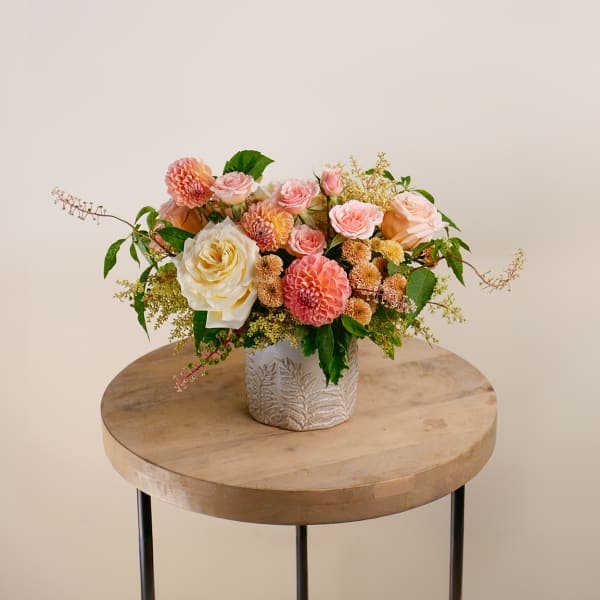 Peach and pink rose arrangement in a patterned ceramic vase