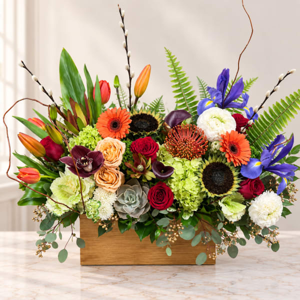 Colorful mixed flower arrangement in a wooden box with tall branches