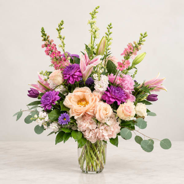 Mixed pink and purple flowers arranged in a clear glass vase